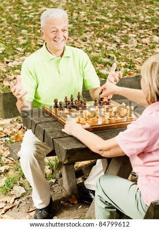 Happy old people playing chess in the park.