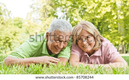 Portrait of happy old people lying on green grass.