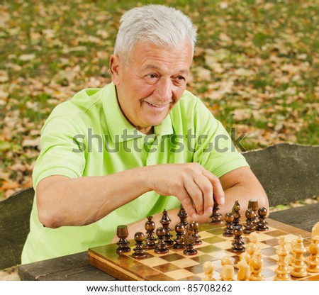 Elderly man playing chess in the park.