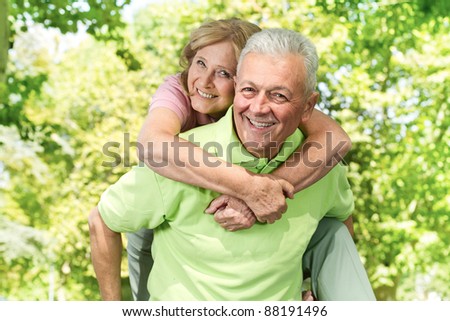 Portrait of happy senior man giving piggyback ride outdoors.