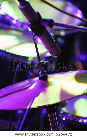 Rock concert series: drum set with microphone, lit by purple and green