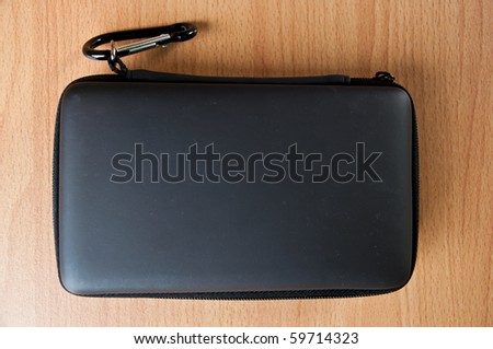 Shiny black plastic box with zipper on wood background
