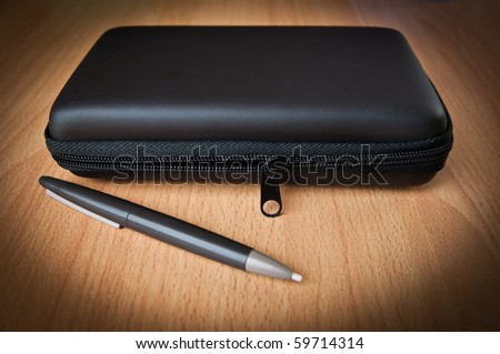 Shiny black plastic box with pen on wood background