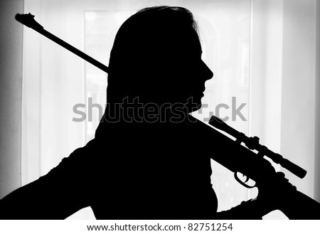 The woman silhouette with gun against a window