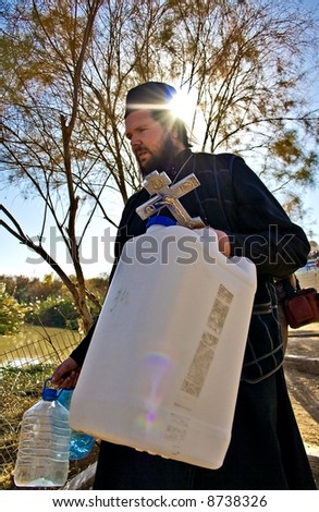 Orthodox Christian filling a bottle with Jordan river Holy Water, Jesus Baptism site, Israel