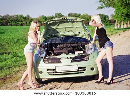 Two sexy blonde girls stand by the broken car and don\'t know what to do