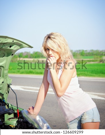 Blonde girl stands near the broken car and don\'t know what to do