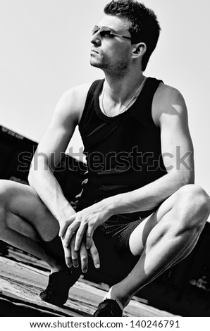 Fashion shot: portrait of a handsome young man wearing sunglasses. Black and white