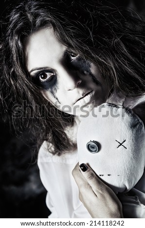 Horror shot: the sad strange girl with moppet doll in hands. Closeup portrait