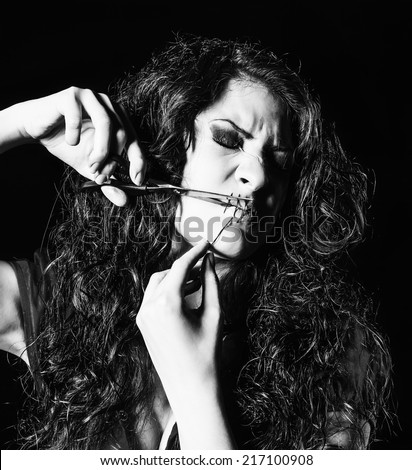 Horror shot: strange girl with mouth sewn shut cutting the thread. Monochrome