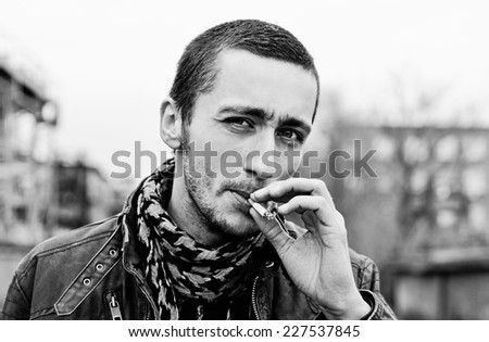 Closeup portrait of a handsome smoking young man. Black and white