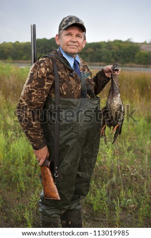 man with gun after hunting bring a duck