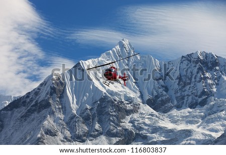 red helicopter is flying between snow mountains peak