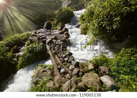 sun rays and bridge cross waterfall