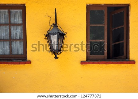 Old yellow wall, window and lamp in Coyoacan, Mexico.