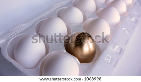 Dozen white eggs, with one of the eggs in the foreground painted a bright metallic gold.