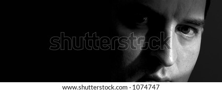 Black and white closeup of a man\'s face, with the right side mostly hidden in shadow.