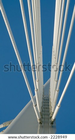Close-up of the tip of the spire on the Provencher Bridge in Winnipeg, showing the convergence of support cables and a frighteningly high access ladder.