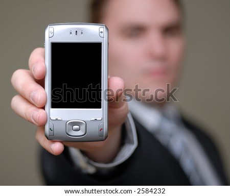 Young businessman holding cell phone towards the camera. Shallow depth of field.