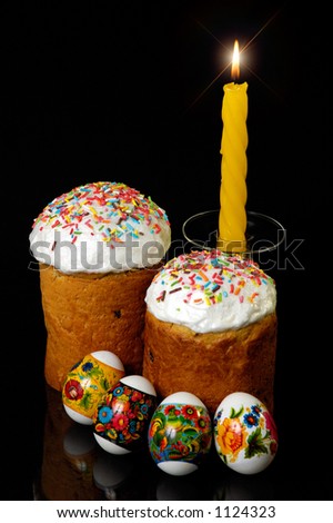 Easter cakes eggs and a candle on a table cloth still life Isolated on black background