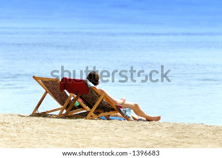Man and woman in chairs resting on the beach near sea