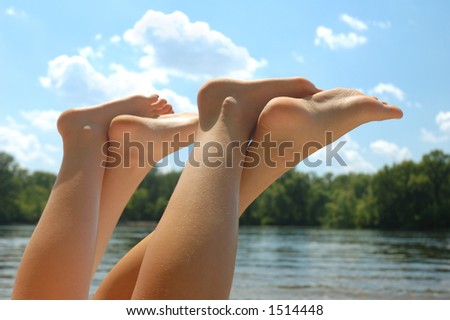 Young women feet in the air in the sun on the beach summer vacation concept