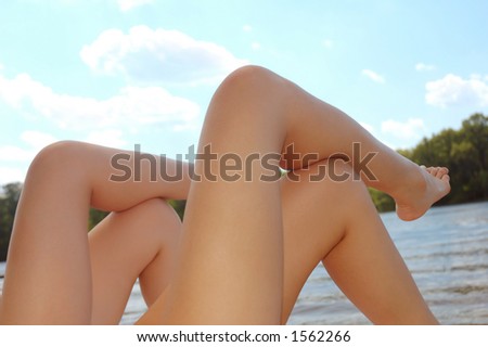 Young women lying in the sun on the beach with their legs in the air summer vacation concept