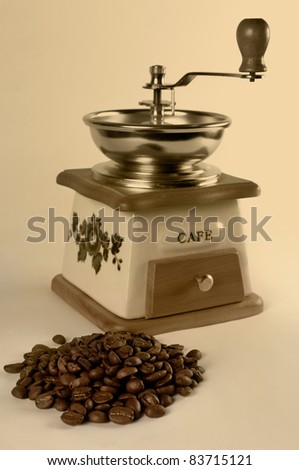 Vintage stylized coffee grinder and a pile of coffee beans close-up Isolated Sepia toned