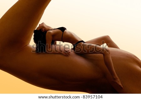 Beautiful young woman in bikini resting on a man\'s biceps. Fitness, tanning, health and beauty concept.
