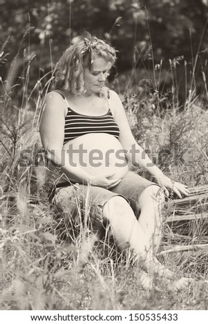A beautiful pregnant woman takes some time to sit and relax outside before the baby arrives.