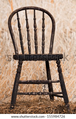 Very old and  peeling paint chair in a field of long grass.