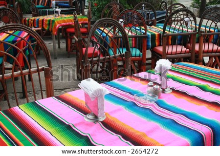 An outside restaurant in Mexico.  Colorful blankets for table cloths