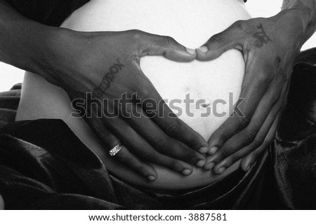 father to be holding his hands in a heart shape