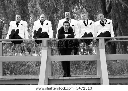 Groomsmen and a groom in black and white tuxedos