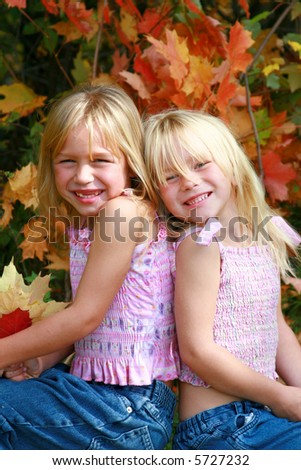 Fall portraits  of twin little girls with colorful leaves in background.