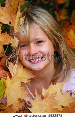 Cute little girl in all the orange fall leaves.