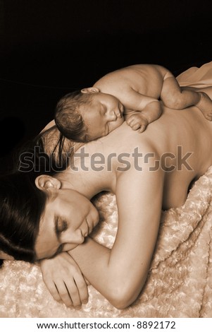 Mother with her newborn baby sleeping on her back for a portrait.