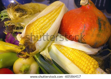 Sweat corn surrounded by autumn vegetables, like pumpkin, pepper, etc.
