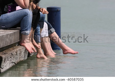 Young girls hanging their legs into the water on the dock