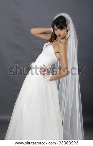Young, beautiful bride posing in wedding clothe in studio