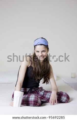 Young woman in the bed, with a cup of tea and blinkers in her head