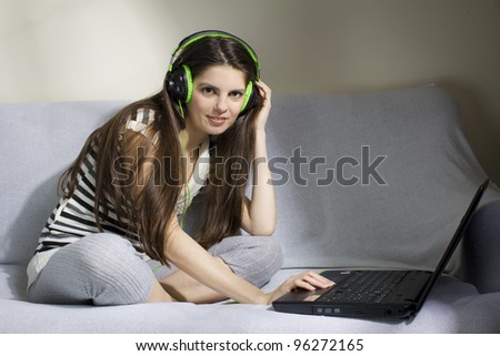 Young woman listening to music on the sofa, with headphone