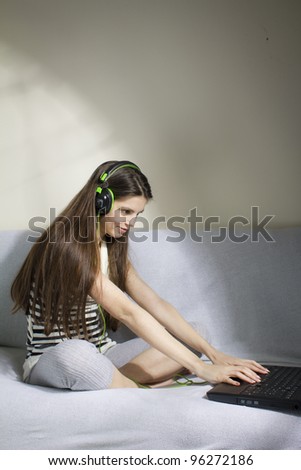 Young woman listening to music on the sofa, with headphone