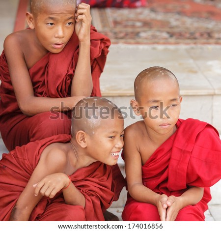 OLD BAGAN, MYANMAR- OCT 15, 2013 : Group of unidentified young novice monks sitting down at Shwedagon Pagoda Temple, Myanmar on October 15, 2013. 89% of the Burmese population is Buddhist.