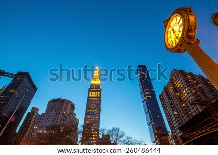 NEW YORK CITY - FEB 11: Sidewalk clock and Flat Iron building, considered to be one of the first skyscrapers ever built, with New York City street view. February 11, 2015 in Manhattan, New York City.