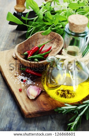 fresh  herbs  with  mezzaluna, olive oil and vegetables on cutting board