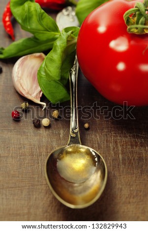 Spoon with Olive Oil and vegetables on wooden table