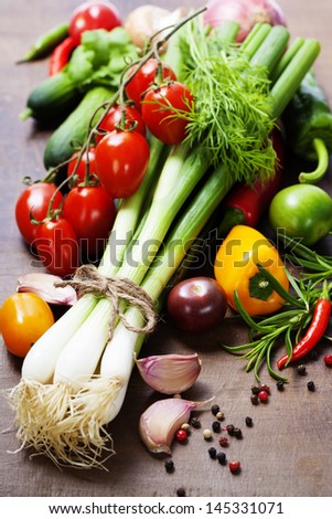 fresh spring onions and vegetables on a wooden board