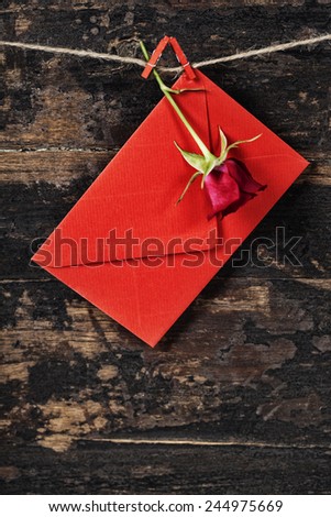 Red  envelop and rose  hanging on the clothesline. On old wood background