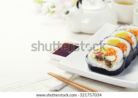 Sushi set, green tea and sakura branch on bamboo mat